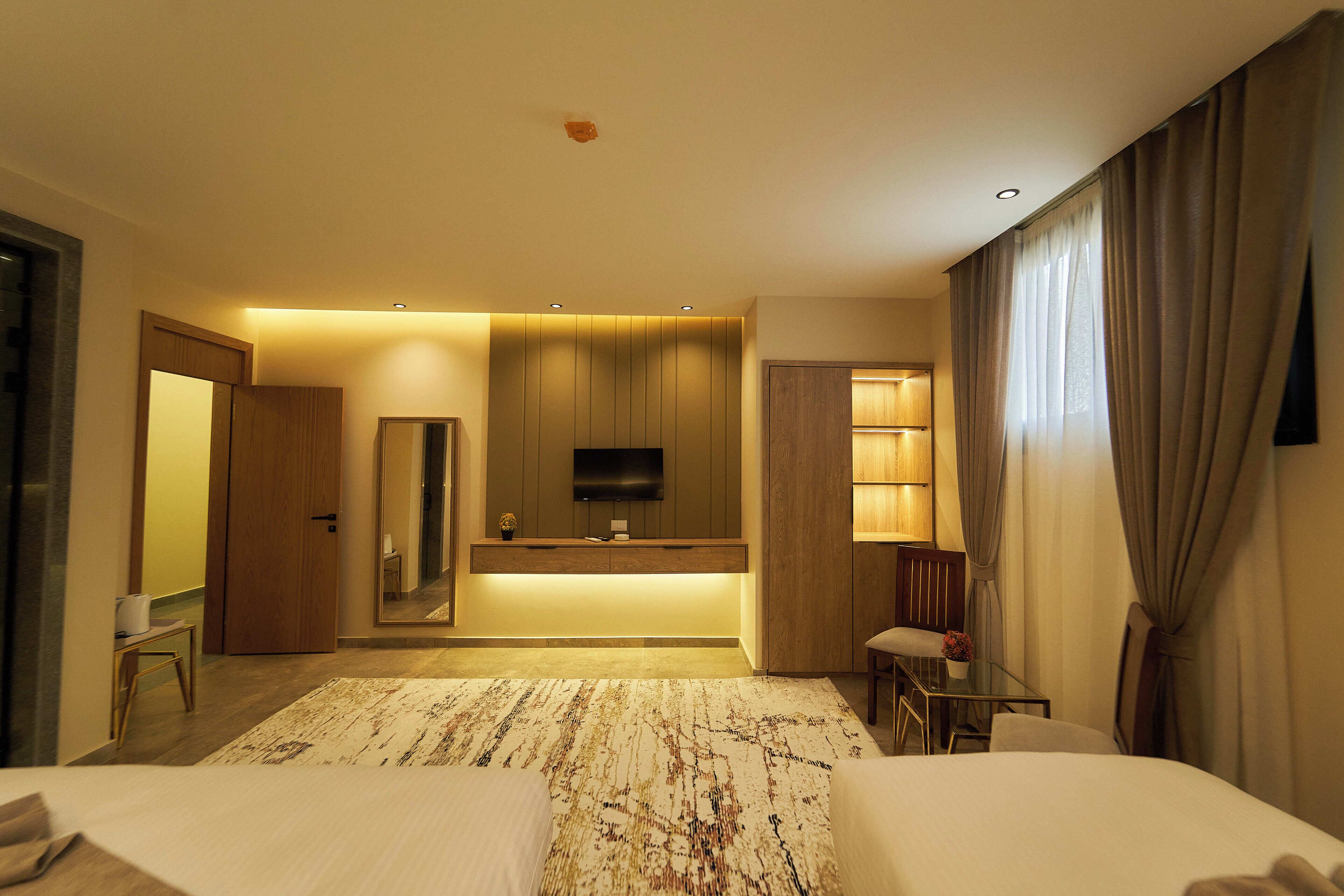 A hotel room with a bed, a desk, a chair, a TV, and a bathroom.