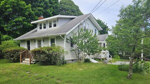 A two-story house with a front porch, a small front yard, and a driveway.