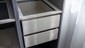 Ein Teil eines Raumes mit einem weißen Schrank und einer Glastrennwand.