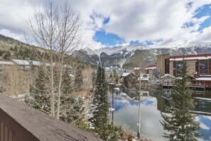 A lakeside view with buildings, snow-covered trees, and mountains in the background. - Tx204 Taylors Crossing 3 Bedroom Condo (Copper Mountain)
