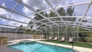 Une piscine extérieure couverte, dotée d’un toit en verre, entourée de chaises longues et d’une petite table.
