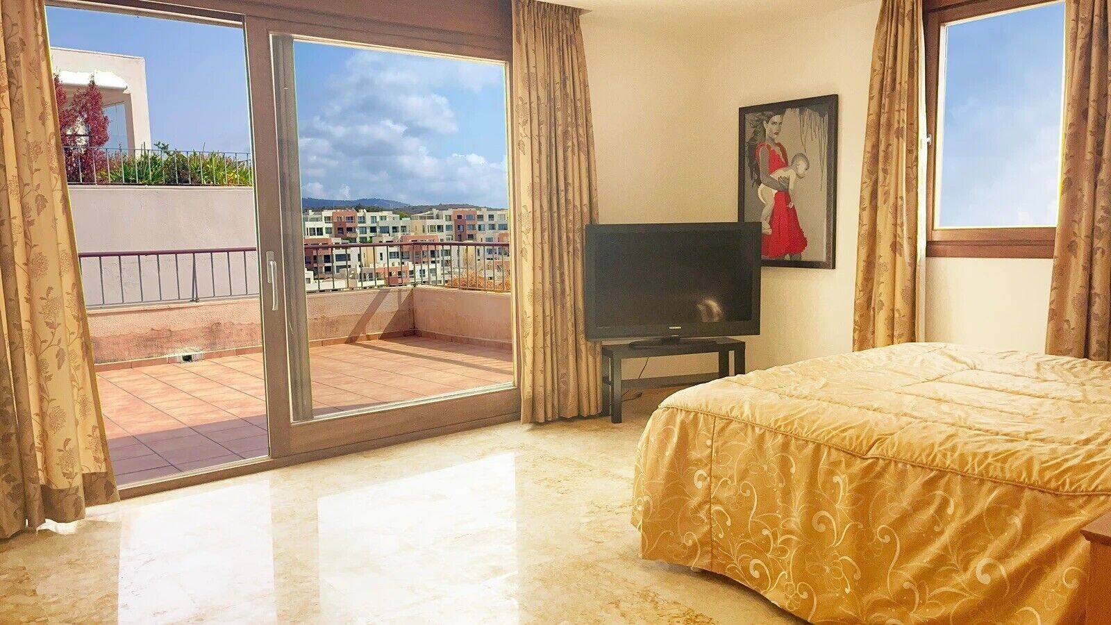 Une chambre d’hôtel avec un lit, une télévision, un balcon donnant sur des immeubles et des rideaux.