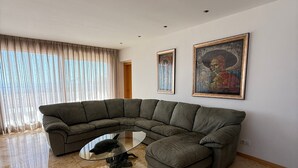 A modern living room with a sectional sofa, a glass coffee table, and a large painting on the wall. - Holiday Home 'Marbella Hills' with Sea View, Wi-Fi and Air Conditioning (Marbella)