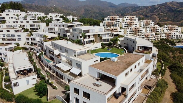 A residential area with modern white buildings, a swimming pool, and a hilly landscape in the background. - Holiday Home 'Marbella Hills' with Sea View, Wi-Fi and Air Conditioning (Marbella)