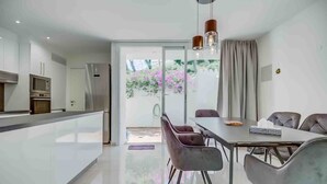 Eine moderne Küche mit Einbauofen, ein Essbereich mit Tisch und Stühlen sowie eine große Schiebeglastür, die auf einen Balkon mit Pflanzen führt.