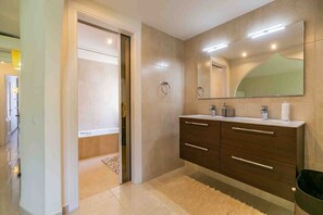 A modern bathroom with a double vanity, a large mirror, and a bathtub. - Holiday Home 'Miraflores Resort Luxury' with Sea View, Wi-Fi and Air Conditioning (Mijas)