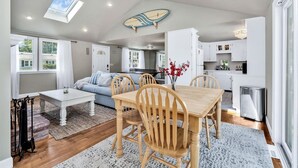 A modern kitchen with white cabinets, a dining area with a wooden table and chairs, and a ceiling fan. - Hyannis Hideaway: Pool, Beaches & Main Street Fun RPAM114 (Hyannis)
