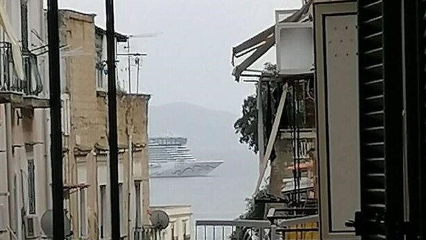 A narrow urban street with buildings on either side, a metal gate, and a view of a distant body of water. - MAISON SOSò NAPLES vacation home Entire apartment in the center of Naples (Napoli)