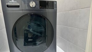Vista frontale di una lavatrice moderna grigia a carica frontale, con pannello di controllo e un'ampia porta in vetro.