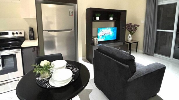 Una cucina moderna con frigorifero, piano cottura e tavolo da pranzo con piatti e un vaso di fiori.