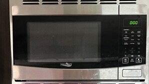 Un four à micro-ondes en acier inoxydable doté d’un écran numérique et d’un panneau de commande, fixé sur un meuble métallique.