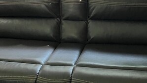 Une partie de l’habitacle d’un véhicule, avec des sièges en cuir noir et une fenêtre équipée de stores horizontaux.