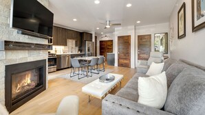 Un salon moderne avec une cheminée, un canapé gris et un coin repas comprenant des chaises et une table.