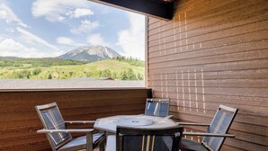 Une terrasse extérieure avec une table et quatre chaises, offrant une vue sur un paysage montagneux.