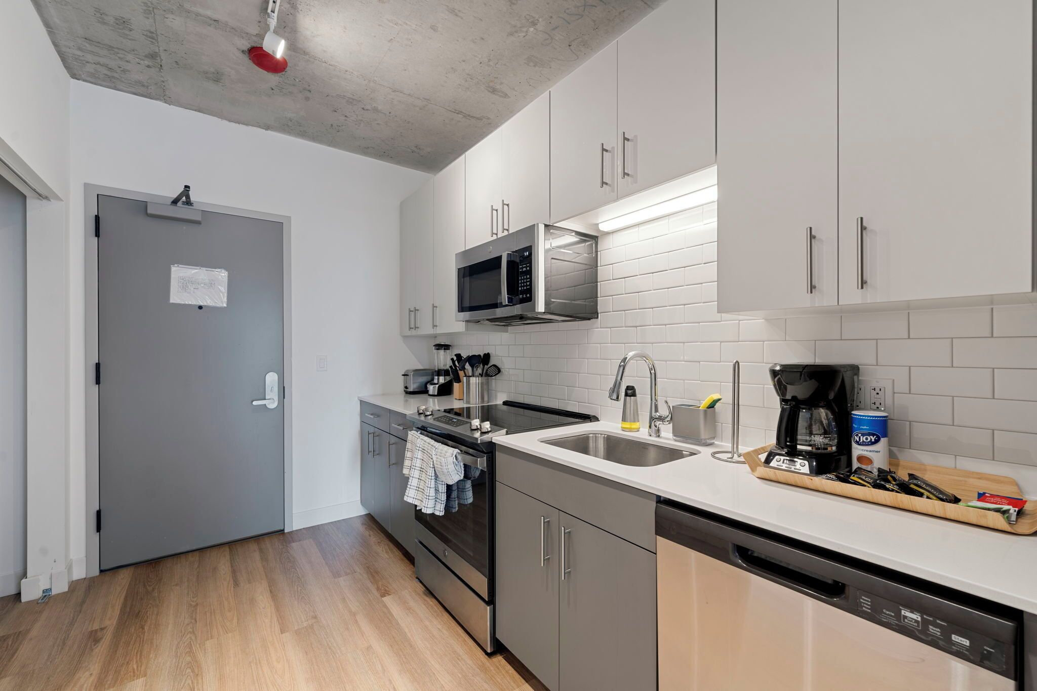 A modern kitchen with stainless steel appliances, a dishwasher, and a wooden countertop.