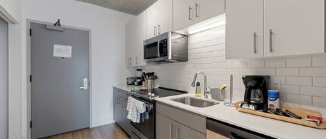 A modern kitchen with stainless steel appliances, a dishwasher, and a wooden countertop.