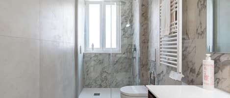 Un baño moderno con ducha de vidrio, inodoro y tocador con espejo.