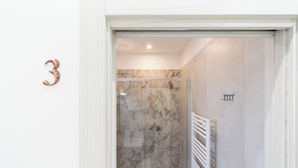 A bathroom with a glass shower enclosure, marble walls, and a white radiator. - Saint Nicholas House by Wonderful Italy (Bari)