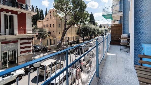 A balcony with a view of a street, a building with a green dome, and a blue tiled wall. - Saint Nicholas House by Wonderful Italy (Bari)