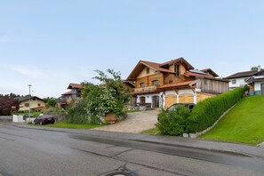 A residential building with a sloped roof, a front porch, and a driveway leading to a parked car. - Apartment 'Walcher Alm' with Lake View, Shared Terrace and Wi-Fi (Höslwang)