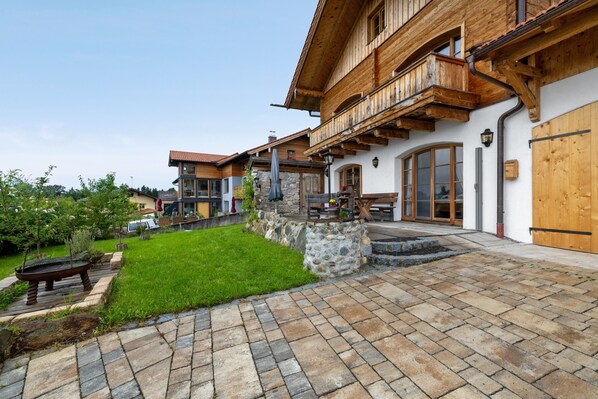 A traditional chalet with a stone facade, wooden balconies, and a paved courtyard. - Apartment 'Walcher Alm' with Lake View, Shared Terrace and Wi-Fi (Höslwang)