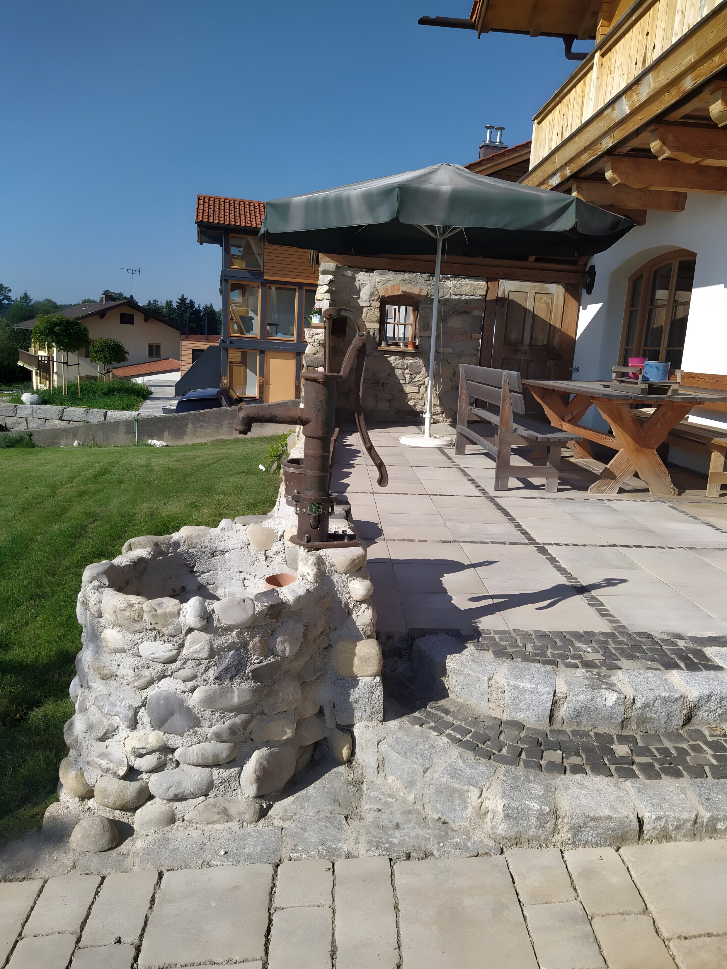 A stone well, wooden benches, and a building with a tiled roof.