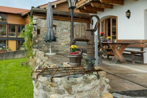 A rustic outdoor area with a stone wall, a wooden bench, and a metal structure resembling a water pump. - Apartment 'Walcher Alm' with Lake View, Shared Terrace and Wi-Fi (Höslwang)