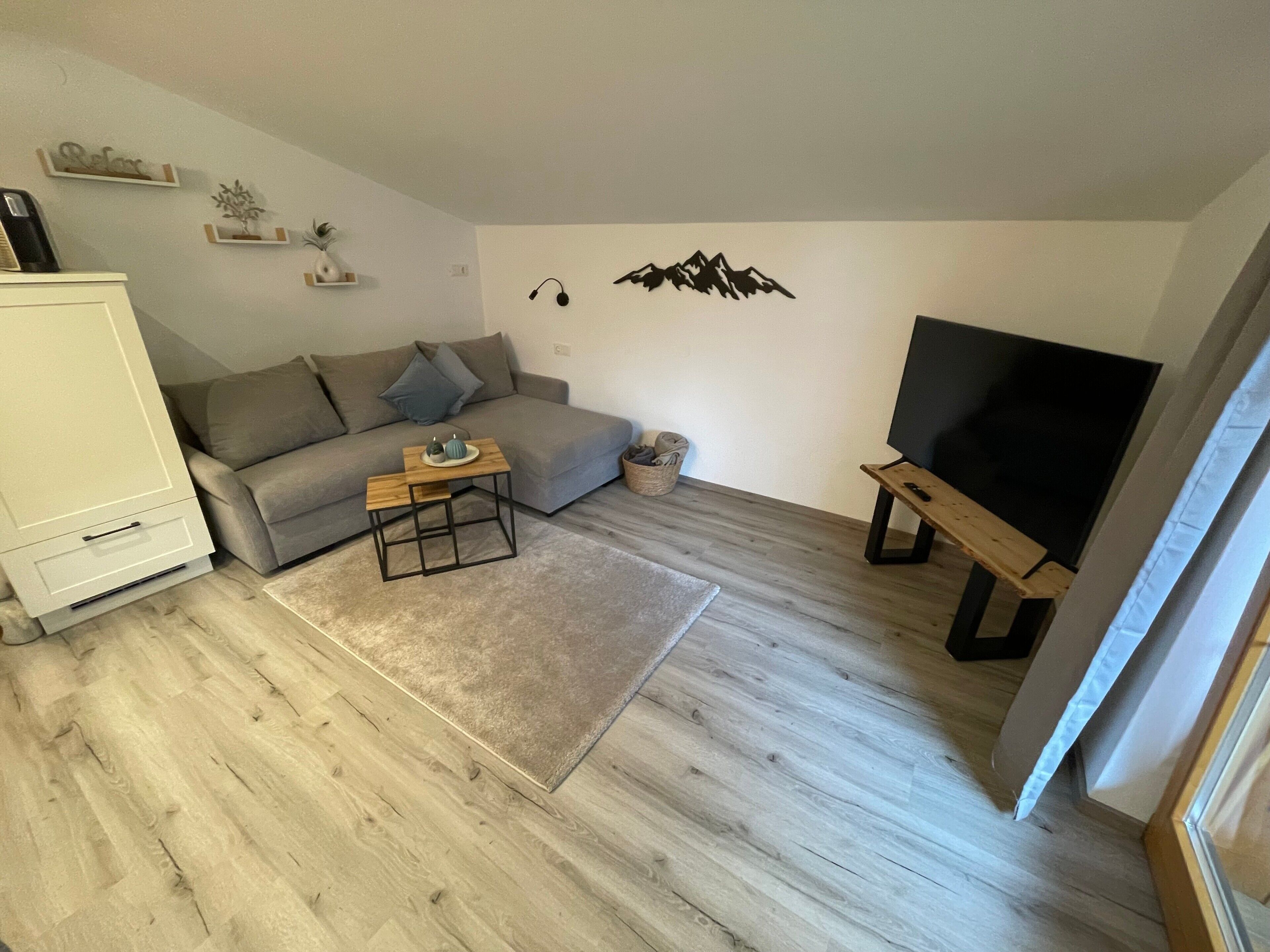 A living room with a sofa, a coffee table, a TV stand, and a flat-screen TV.