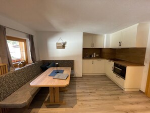 Une cuisine compacte avec des meubles en bois, un four encastré et un coin repas comprenant un banc et une table.