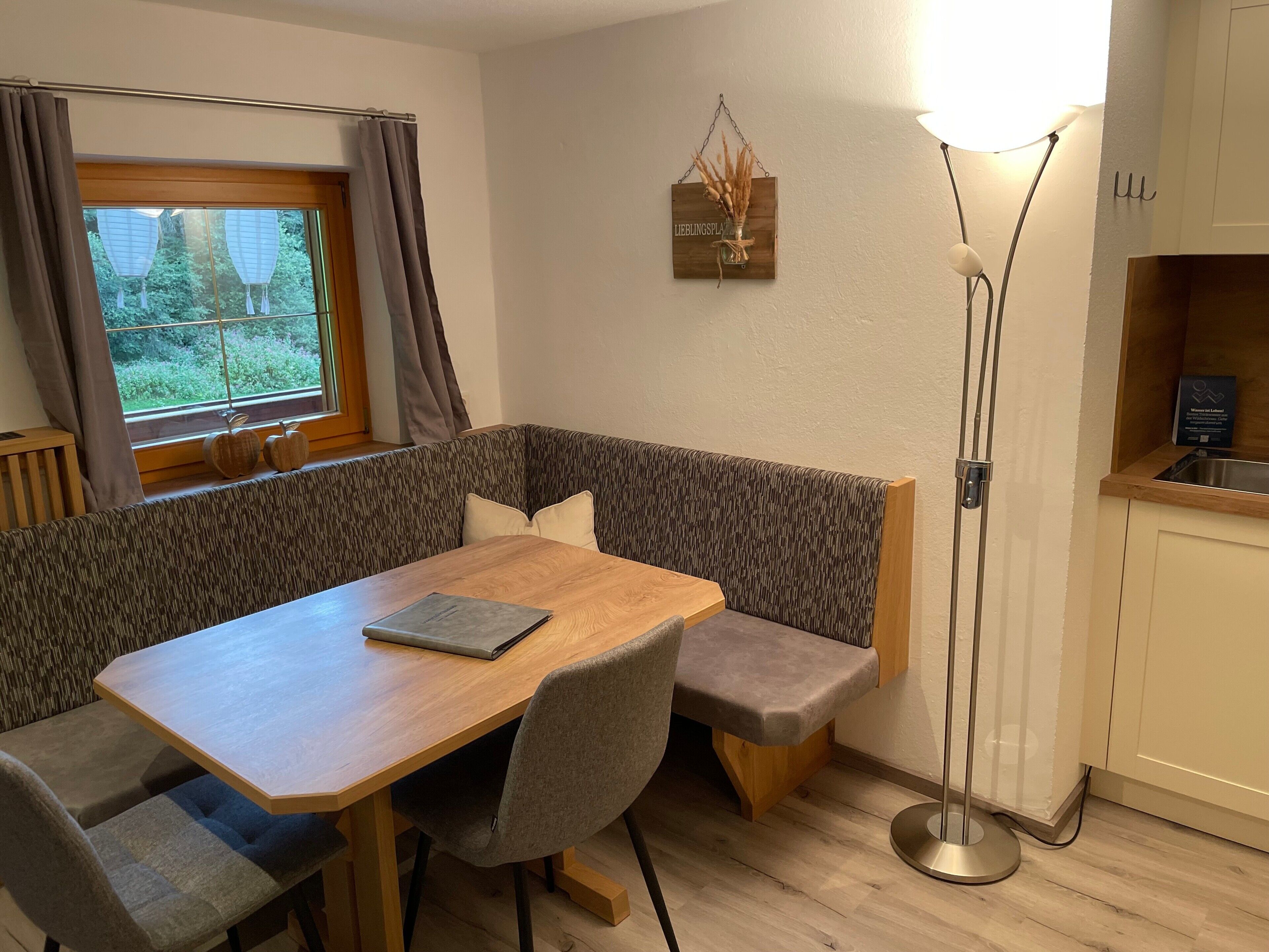 Ein Essbereich mit einem Holztisch, gepolsterten Bänken und einer Stehlampe.