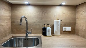 Cozinha moderna com pia de aço inoxidável, painel de madeira e iluminação embutida.
