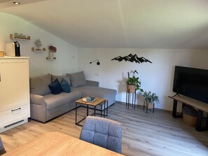 A modern living room with a sofa, a coffee table, a TV, and decorative plants.