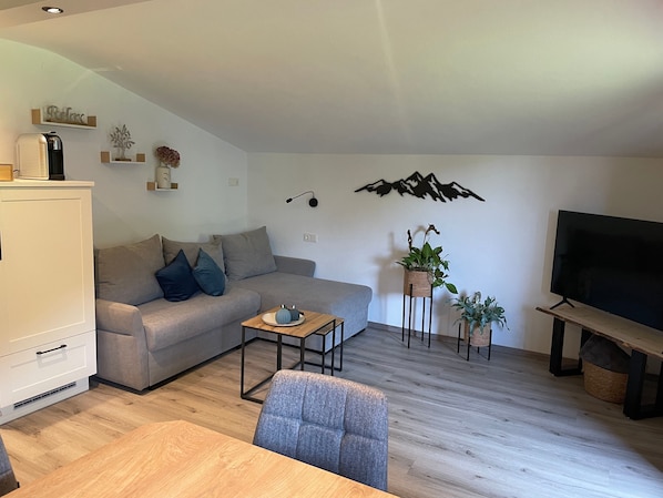 Un salon moderne avec un canapé, une table basse, un téléviseur et des plantes décoratives.
