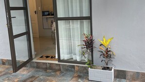 A modern entrance with a glass door, a potted plant, and a wall-mounted light fixture. - Comfortable Open-Plan Studio Stay — 36 On Blougom, Midrand (Midrand)