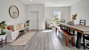 Una sala moderna con una mesa de comedor de madera, sofá blanco y un espejo grande.