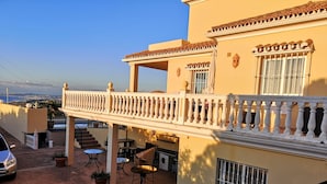 A building with a balcony, outdoor seating, and a view of the city. - Apartment 'Villa Roca' with Sea View, no kids under 10 year. (Málaga)