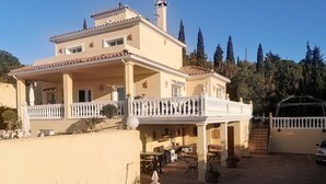 A two-story building with a balcony, outdoor seating, and a gated entrance. - Apartment 'Villa Roca' with Sea View, no kids under 10 year. (Málaga)