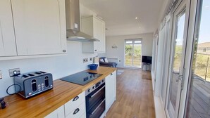 A modern kitchen with white cabinets, a wooden countertop, a built-in oven, and a toaster.