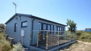 A single-story house with a glass enclosure at the front, a satellite dish on the roof, and a clear blue sky.