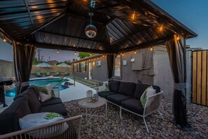 An outdoor patio area with a pool, seating, and string lights. - Spacious 5BR Retreat + Game Room (Phoenix)
