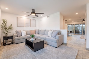 A modern living room with a sectional sofa, a coffee table, and a ceiling fan. - Old Town Living • Walk to Dining, Bars & Fun (Scottsdale)
