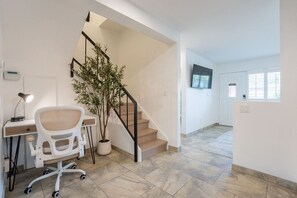 A modern interior with a staircase, a desk with a chair, and a potted plant. - Old Town Living • Walk to Dining, Bars & Fun (Scottsdale)