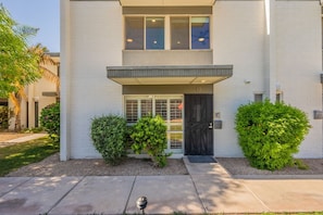 A two-story building with a black front door, a small porch, and two potted plants. - Old Town Living • Walk to Dining, Bars & Fun (Scottsdale)