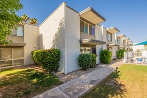 A row of modern, single-story townhouses with a uniform architectural style, featuring balconies and a well-maintained lawn. - Old Town Living • Walk to Dining, Bars & Fun (Scottsdale)
