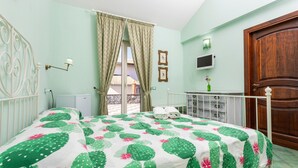 A bedroom with a bed, a window with curtains, a door, a TV, and a small table with a vase. - Bed and Breakfast 'Luna' with Sea View, Shared Pool and Wi-Fi (Calatabiano)