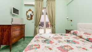 A bedroom with a bed, dresser, TV, and a view through the window. - Bed and Breakfast 'Sole' with Sea View, Shared Pool and Wi-Fi (Calatabiano)
