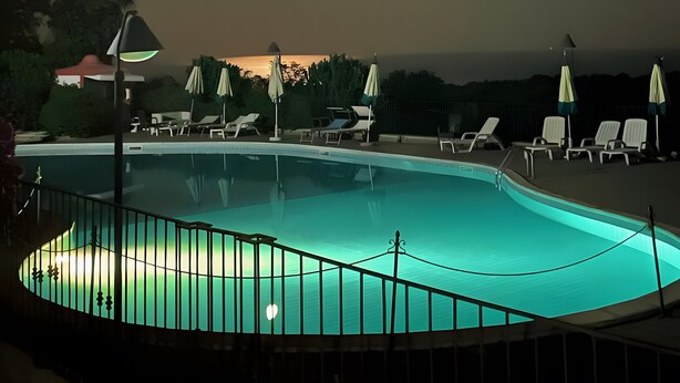 A pool with a fence, lounge chairs, and umbrellas under a night sky with a visible moon. - Bed and Breakfast 'Sole' with Sea View, Shared Pool and Wi-Fi (Calatabiano)