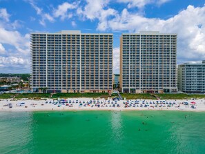 A beachfront hotel with multiple high-rise buildings, a sandy beach, and clear turquoise waters.