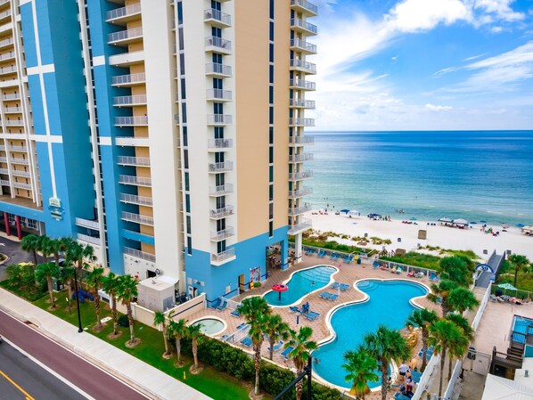 A high-rise hotel with a pool area, beach access, and a view of the ocean.
