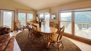 A spacious dining area with a large wooden table and chairs, surrounded by large windows offering a view of the outdoors. - TM-2  Cox Retreat Amazing 6-Bedroom Hot Tub (Beech Mountain)